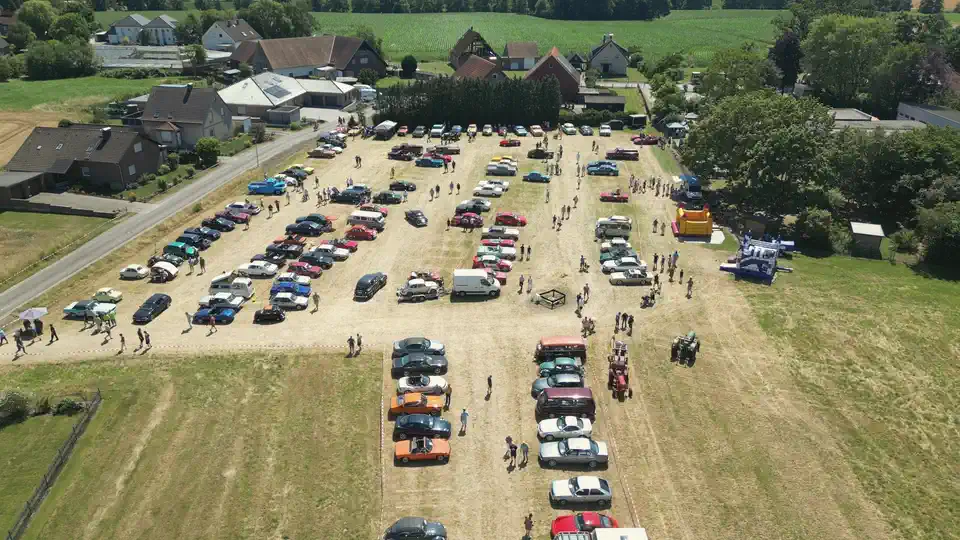 Eigene Luftaufnahme: ein Oldtimertreffen auf einer Wiese in Ahle, dahinter Höfe, Bäume und Felder
